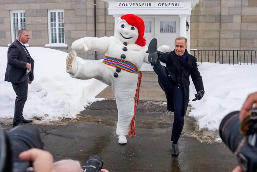 El primer ministro Mark Carney abraza y da una patada juguetona con el personaje de carnaval de invierno de la ciudad de Quebec. Foto/ Lars Hagberg (@hagberd_lars).